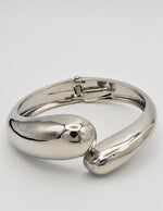 silver bangle bracelet paired with clean girl rings on wrist