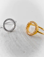 Gold and silver circular earrings on a marble surface
