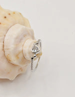 Silver Glow Heart Eternity Ring displayed on a shell, featuring a polished heart gemstone flanked by tiny pavé accents; a minimalist yet romantic gift for her jewellery admired in Montreal jewellery boutiques.