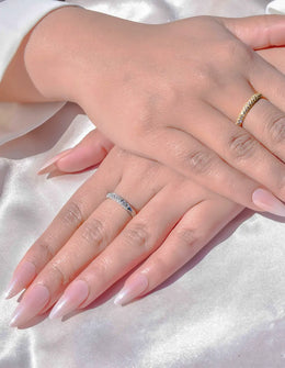 Hand wearing dual-tone crystal wedding band ring on silk fabric