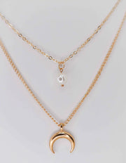 Close-up of minimalist gold necklace with celestial symbols
