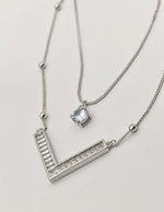 dainty silver initial necklace v pendant close-up on textured background