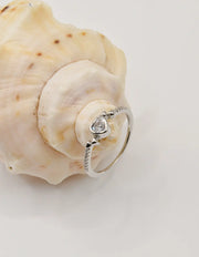 Silver Glow Heart Eternity Ring resting on a natural shell, highlighting its shimmering heart gem and slim band; a romantic piece for Montreal minimalist jewellery lovers and holiday gift ideas in Canada