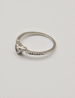 Angled shot of the Silver Glow Heart Eternity Ring on a seashell, showing the heart‑shaped centre stone and elegant pave setting; a clean girl jewellery 2025 favourite and thoughtful gift for her jewellery