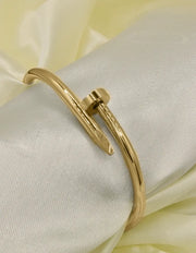Elegant gold twist nail bangle bracelet displayed on satin, perfect Canadian gift idea.